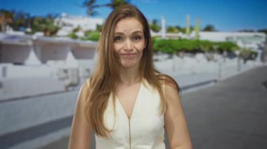 Şehir caddesinde beyaz bina duvarının yanında şüpheli bir ifadeyle parmakla gösteren bir kadın var..