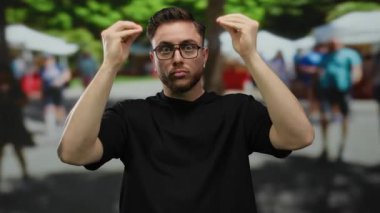 Sakallı ve gözlüklü genç adam hareketli bir şehir caddesinde hareketli, hareketli şehir ortamına karışıyor, bulanık hareketli figürlerle çevrili..