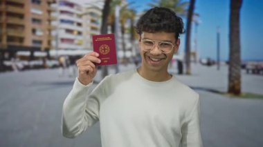 Şehirde palmiye ağaçlarının altında sırıtırken Yunan pasaportu taşıyan adam, seyahat özgürlüğü heyecanı.