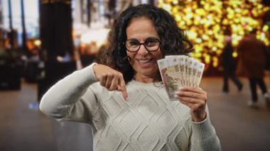 Dışarıda elinde Rus banknotları tutan ve şehir ışıklarıyla çevrili kalabalık bir caddede gülümseyen para ve finansmanı ön plana çıkaran bir kadın..