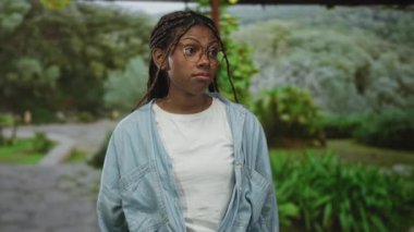 Yeşillikler arasında park yolunda dururken örgü ören ve bardakları iten kadın; sessiz tefekkür.