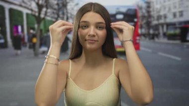 Kalabalık bir şehir caddesinde kadın şakaklarına dokunuyor. Yüzü ve gözleri gergin bir hareketle kapalı, stresle başa çıkıyor..