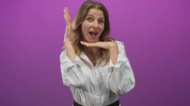 Gülümserken ve stüdyoda canlı mor arkaplan ile poz verirken, elleri ve yüzü vurgulayan bir kadın..