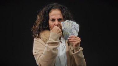 Romen banknotlarını elinde tutan orta yaşlı bir kadın, izole edilmiş bir siyah arka plana karşı, mali güç ve kararlı bir ifadeyle gücü sembolize ediyor..