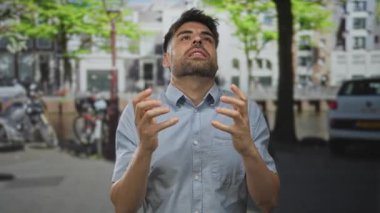 Yeşil ağaçların altında park halindeki bisiklet ve arabalarla dolu, hareketli bir caddede adam el kaldırıyor. Hayal kırıklığı..