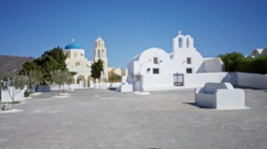 Beyaz yıkanmış kubbeler ve alçak duvarlar ile Santorini kilise meydanı, yumuşak bulanık bokeh arkaplan ve boş asfalt ön plan; arkaplan, arkaplan, telif alanı, sakin.