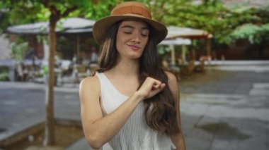 Gülümseyen genç İspanyol kadın restoran terasında göğsüne yumruk tokuşturuyor; kardeşlik dayanışması.