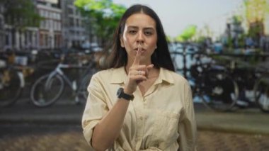 Kanal boyunca sessizlik için parmakları dudaklarına kadar uzanan kadın ve park etmiş bisikletler, yüzük takan ve akıllı gözlük takan sessiz bir gizlilik..