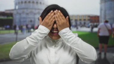 Gülümseyen genç bir kadın İtalya 'daki sidik kulesinin yanında sevinç ifade ediyor, açık şehir ortamında mutluluk ve heyecan sergiliyor..