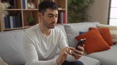 Modern bir oturma odasında, rahat ve şık bir atmosfer izlenimi veren kitap rafları ve yastıklarla bir koltukta oturan bir adam..