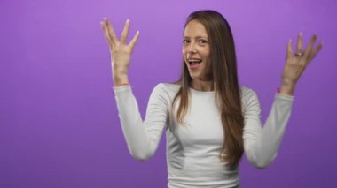 Mor stüdyoda çimdiklenmiş parmaklar ve eller öne doğru hareket ederken gülümseyen bir kadın; oyuncu bir davet.