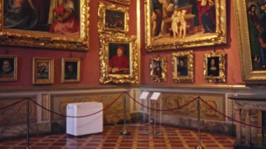 Altın çerçeveli tablolar, mermer dado ve fayanslı zemin, kadife ip bariyerleriyle yumuşakça bulanık ve çözülmüş arka plan; arka plan telif alanı sakinliği.