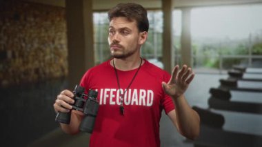 Can kurtaran elinde dürbün ve ıslık tutan kırmızı gömlek ve iple kapalı havuzu tarayan bir adam..