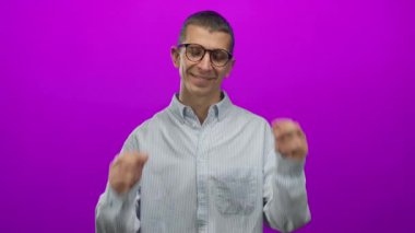 Beyaz adam gülümserken parlak pembe arka planda gözlük çıkartıyor, çizgili bir tişört giyiyor ve neşeli bir ifade takınıyor, tefekkür ve mizah anı yakalıyor..