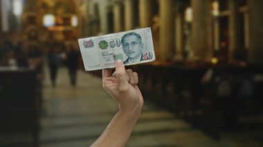 Kilisede elinde Singapur Doları banknotları tutan adam. Geçmişi bulanık. Dini mimari ve tefekküre dayalı bir atmosferi tasvir ediyor..