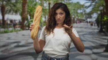 Baget tutan kadın ve işaret parmağı beyaz tişörtlü ve açık hava marketlerinin yanındaki kot pantolonlu bir palmiye ağacının işaret parmağı; uyarı.