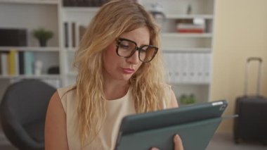 Bir binada tablet tutan bir kadın, büyük gözlüklü okumak ve cihazın görünür el; düşünceli iş yansıması.