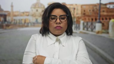 Beyaz gömlekli kendine güvenen kadın kentin arka planında bulanık Roma harabelerine karşı duruyor. Şehir özünü ve tarihi çekiciliğini yakalıyor.