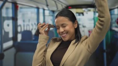 Otobüste gülümseyen bir kadın, gezici telefondan müzik dinlerken neşeli bir şehirli havası yaratıyor..