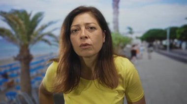 Sarı tişörtlü kadın dudakları ayrıldı ve kameraya odaklandı deniz kenarında bir sokakta öne eğilerek; tefekkür.