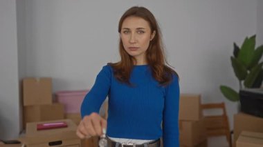 Yeni evin anahtarlarını elinde tutan kadın, parlak bir oturma odasında kutuları taşıyan, genç ve gülümseyen, yeni bir başlangıç ya da yeni bir eve taşınmayı önemseyen bir kadın..