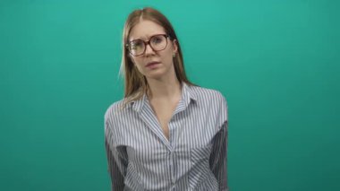 Sarışın kadın, gözlük takarken başını eğiyor ve saçlarını tarıyor..