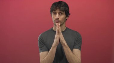 İnsan, stüdyoda kırmızı duvara karşı bastırılmış avuç içi dua hareketini nazikçe yukarı bakarken kapalı gözlerle tutar; umut.