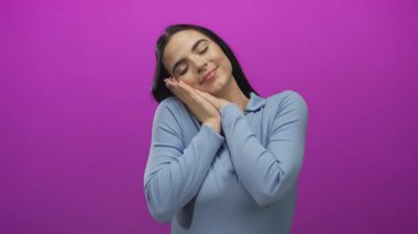 Mavi gömlekli genç İspanyol kadın sakin duygu ifadesi için canlı pembe duvar arkasında uyuyor.