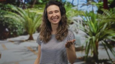 Güneşli, yeşil bir parkta, palmiye ağaçlarının ve kaldırım yollarının yanında uzanan bir elle öpüşen kadın..