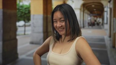 Şehir sokağında neşeli ve neşeli bir atmosferi olan genç bir kadın neşeyle kamerayı işaret ediyor..