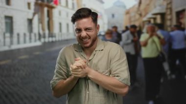 Gündüz vakti şehir sokaklarında kaldırım taşı yolda gülümseyen sakallı genç bir adam canlı bir şehir manzarası yakalıyor.
