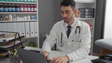 Genç bir erkek doktor klinikte boyun ağrısı çekiyor. Arka planda tıbbi malzeme rafları var. Stresli bir çalışma ortamı var..