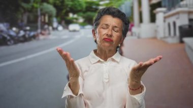 Gri saçlı yaşlı kadın gün boyunca bir şehir caddesinde endişeli görünüyor, duygu ve içgözlem dolu bir şehir yaşamının bir anını yakalıyor..