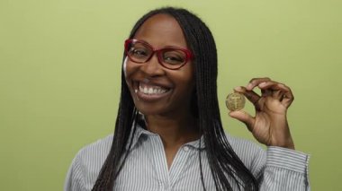 Sarı arkaplan önünde sanal para tutan gülümseyen kadın modern kripto para birimini temsil ediyor..