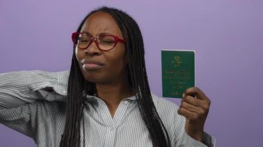 Mor arka planda Suudi Arabistan pasaportu taşıyan, gözlüklü ve çizgili gömlekli, düşünceli bir kadın..