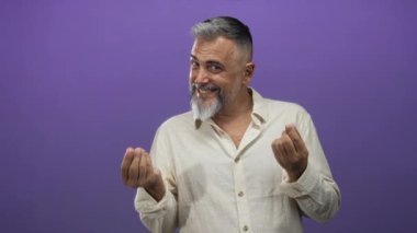 İki eli mor stüdyo seti içinde kıvrılmış, gülümseyen ve işaret eden adam; yaramaz davet.