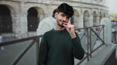 Roma 'da şehir merkezindeki Roma Kolezyumu' nda küçük boy el kol hareketi yapan genç bir adam. Çekici İspanyol erkeği yaratıcılığını ifade ediyor..