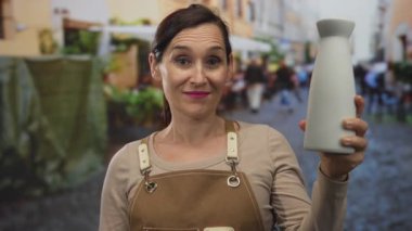 Genç İspanyol esnaf seramik kavanozu tutuyor ve sokak tabelasına imza atıyor. Onaylı gurur işçiliği kalitesi.