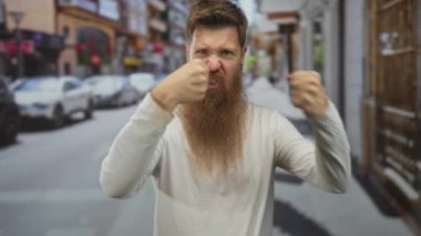 Binaların ve park halindeki arabaların kuşattığı dar bir şehir sokağında yumruklarını sıkmış bir adam, öfke saldırganlığı hüsranı..