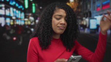 Akşamları kalabalık şehir sokağında elinde akıllı telefon tutan kadın sokak lambaları altında kargaşa çıkarıyor..