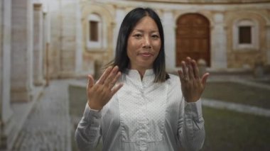 Elleri havada bir kadın, yüzüklerini gösteriyor ve kameraya gülümsüyor. Eski şehir taş avlusunda kaldırımlı sokak ve kapı aralığı olan bir ev. Mutluluk..