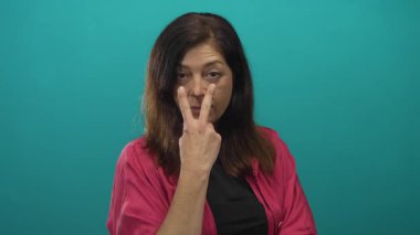 Orta yaşlı İspanyol kadın bir stüdyoda el dürbünü hareketi yaparak tetikte bekliyor..