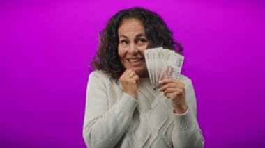 Tayvan banknotları elinde canlı mor bir arka plana gülümseyen, izole ve renkli bir ortamda zenginlik ve memnuniyet duygularını ifade eden bir kadın..