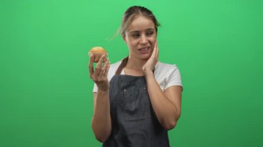 Stüdyoda el ele tutuşan, tırnak yiyen, yeşil arka planda olan kadın. Tereddüt kaygısı..