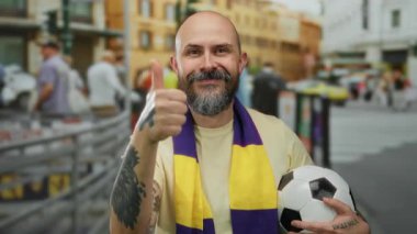 Sakallı ve fularlı neşeli bir adam futbol topunu şehir sokaklarında tutuyor, şehir manzarasının ortasında parlıyor..