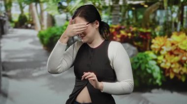 Kumsal kenarındaki canlı bir gezinti güvertesinde, kumral saçlı bir kadın endişeli görünüyor. Tropikal bir geçmişi var. Açık hava yürüyüşünde duygularını sergiliyor..