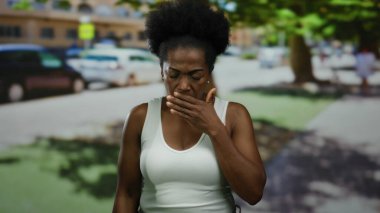 Şehrin bir sokak ortamında esneyen ve sandık tutan bir kadın samimi duygular ve şehir atmosferi sergiliyor..