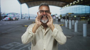 Havalimanı kaldırım kenarında el ele bağıran ve el sallayan, keten gömlekli sakallı, neşeli bir selamlama.