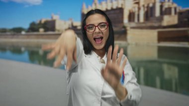 Sahilde gezinen arka planda canlı bir kıyı manzarası olan bilim adamı üniformasıyla neşeyle dans eden kadın..