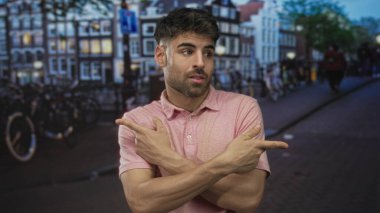 Pembe gömlekli adam şehir caddesinde bisikletlerin arasında kenara bakarken işaret ediyor; belirsizlik kararı.